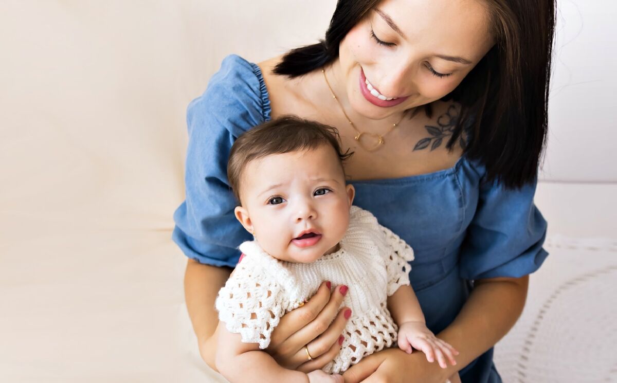 Mãe sorrindo com o bebê recém-nascido no colo, após acompanhamento de doula